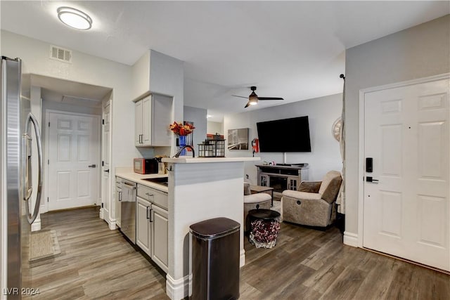 kitchen featuring ceiling fan, sink, dark hardwood / wood-style flooring, kitchen peninsula, and appliances with stainless steel finishes