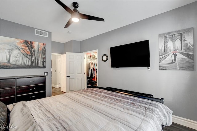 bedroom featuring hardwood / wood-style floors, ceiling fan, a walk in closet, and a closet