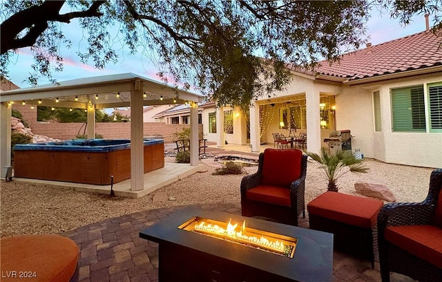 view of patio / terrace featuring a hot tub, fence, and a fire pit