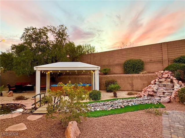 yard at dusk featuring a patio area, a fenced backyard, and a gazebo