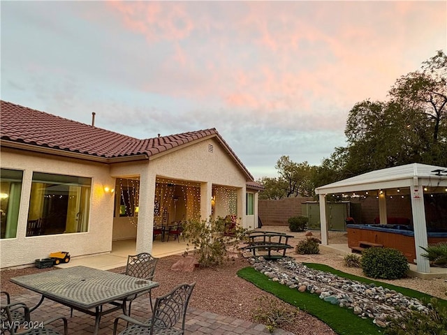 patio terrace at dusk with a gazebo and a hot tub