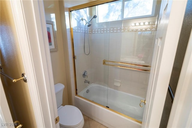 bathroom featuring toilet, tile patterned flooring, and combined bath / shower with glass door