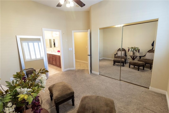 sitting room with light carpet, a ceiling fan, and baseboards