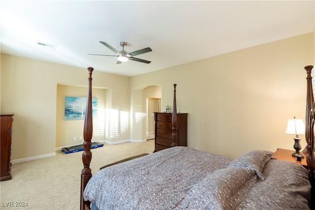 carpeted bedroom with a ceiling fan, arched walkways, visible vents, and baseboards