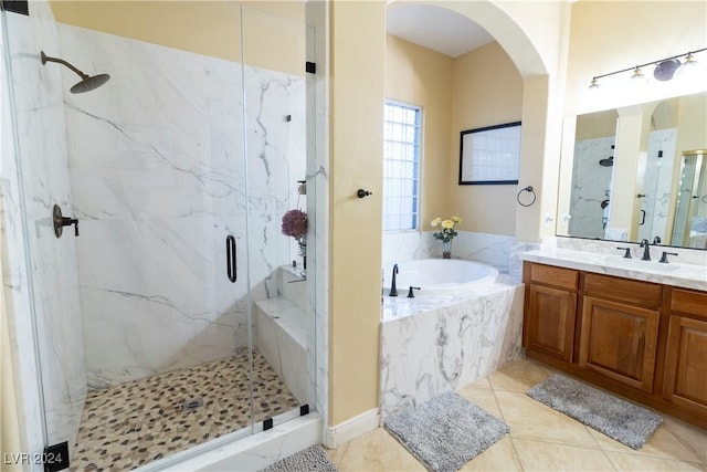 bathroom with tile patterned floors, a marble finish shower, a bath, and vanity