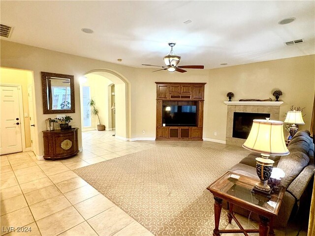 tiled living room with a fireplace and ceiling fan