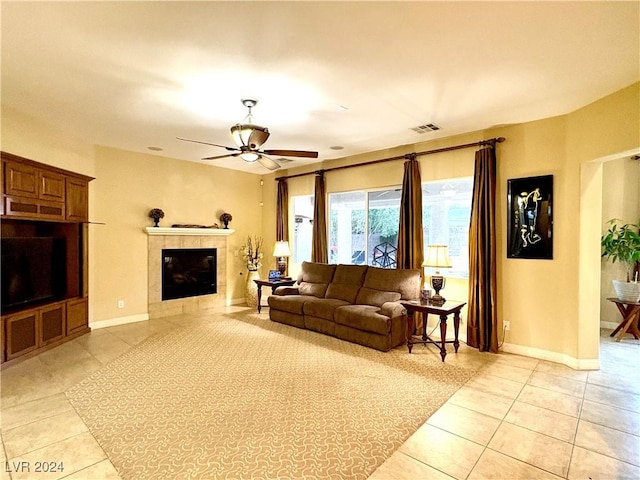 tiled living room featuring ceiling fan and a tiled fireplace