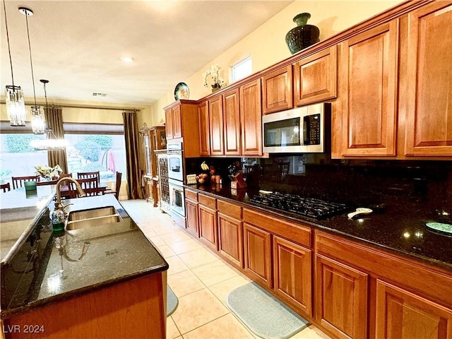 kitchen featuring backsplash, black gas cooktop, dark stone counters, sink, and light tile patterned flooring