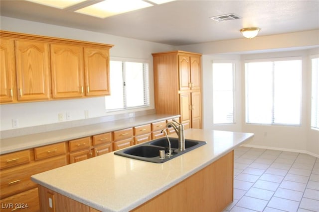 kitchen with a center island with sink, light tile patterned floors, and sink