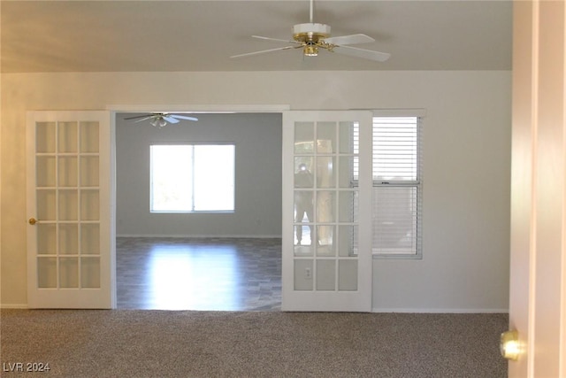 spare room featuring dark colored carpet, ceiling fan, and french doors