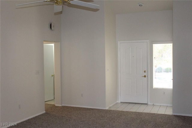 carpeted foyer with a high ceiling, a wealth of natural light, and ceiling fan