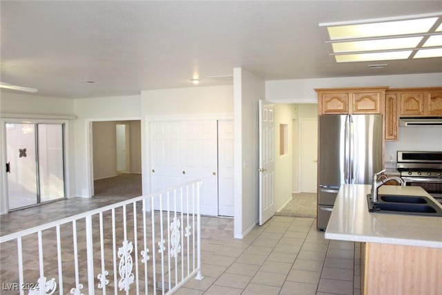 kitchen featuring sink, stainless steel appliances, an island with sink, light tile patterned floors, and exhaust hood