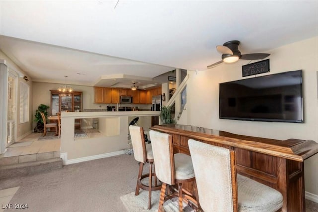 bar featuring pendant lighting, light colored carpet, stainless steel appliances, and ceiling fan with notable chandelier