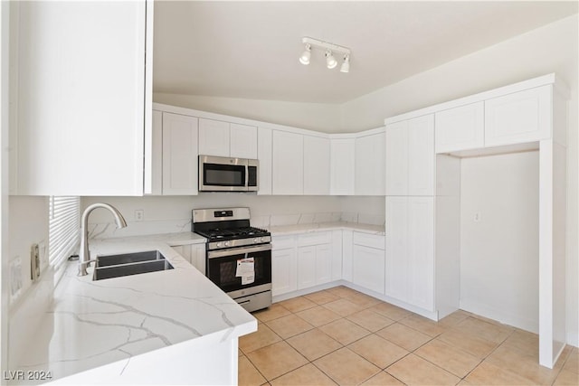 kitchen with light stone countertops, stainless steel appliances, sink, white cabinets, and lofted ceiling