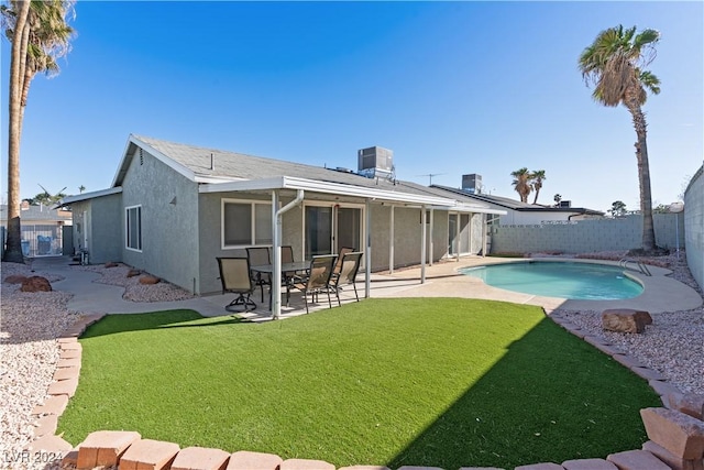 rear view of house featuring a fenced in pool, a yard, and cooling unit