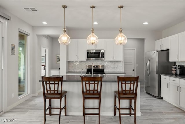 kitchen featuring white cabinets, a kitchen breakfast bar, stainless steel appliances, and pendant lighting