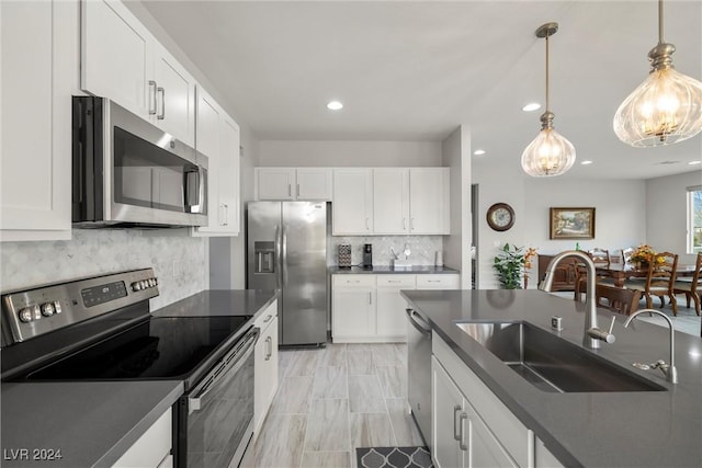 kitchen featuring hanging light fixtures, sink, white cabinets, and stainless steel appliances