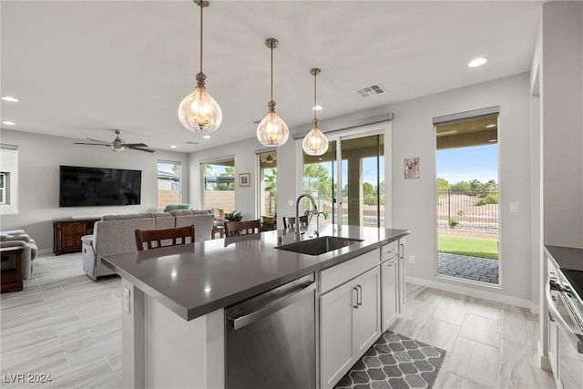 kitchen featuring white cabinets, decorative light fixtures, a center island with sink, and appliances with stainless steel finishes