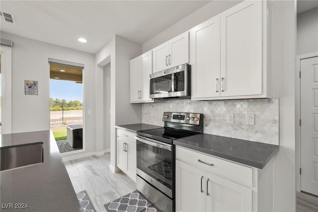 kitchen featuring white cabinetry, sink, backsplash, light hardwood / wood-style floors, and appliances with stainless steel finishes