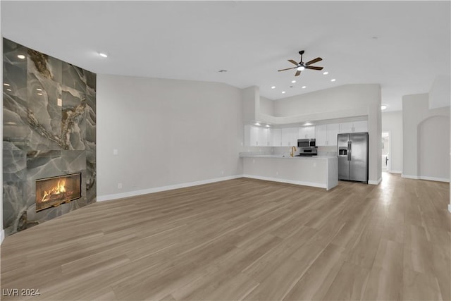 unfurnished living room featuring ceiling fan, sink, a fireplace, and light hardwood / wood-style flooring