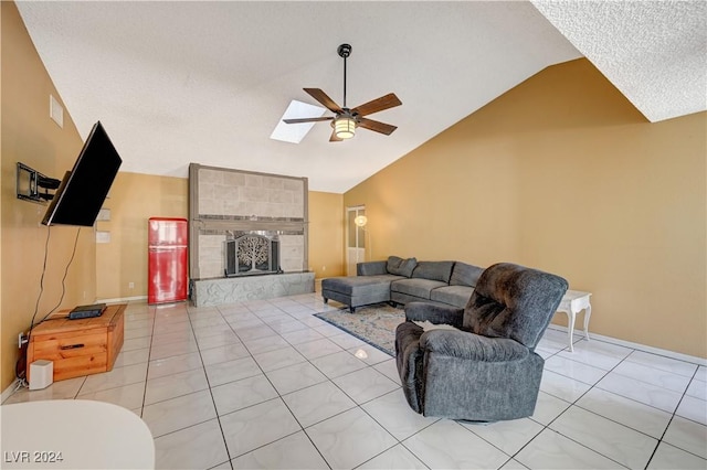 living room featuring ceiling fan, light tile patterned flooring, a fireplace, and a skylight