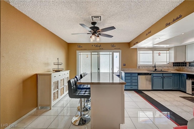 kitchen with dishwasher, sink, decorative backsplash, a textured ceiling, and a breakfast bar area