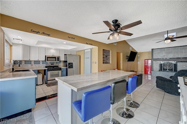 kitchen with a kitchen bar, stainless steel appliances, and a textured ceiling