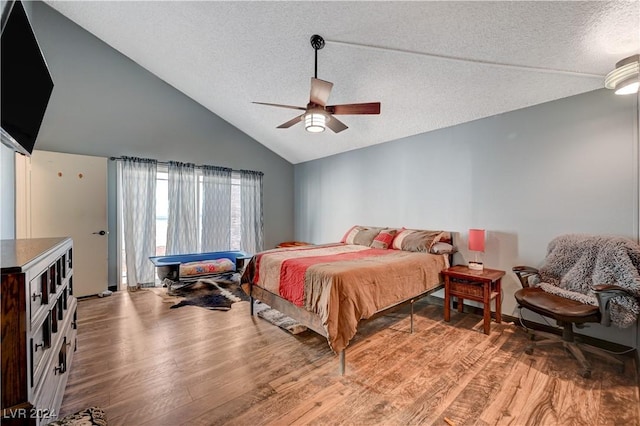 bedroom featuring a textured ceiling, light hardwood / wood-style flooring, vaulted ceiling, and ceiling fan