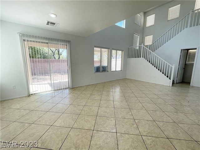 unfurnished living room featuring light tile patterned floors and a high ceiling