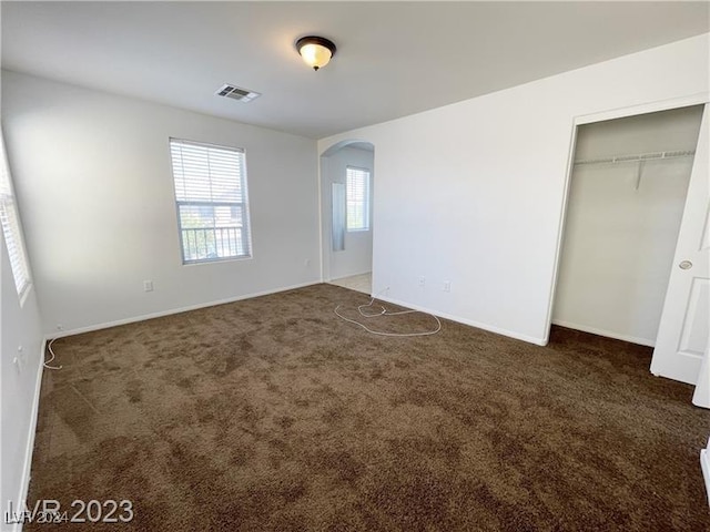 unfurnished bedroom featuring a closet and dark colored carpet