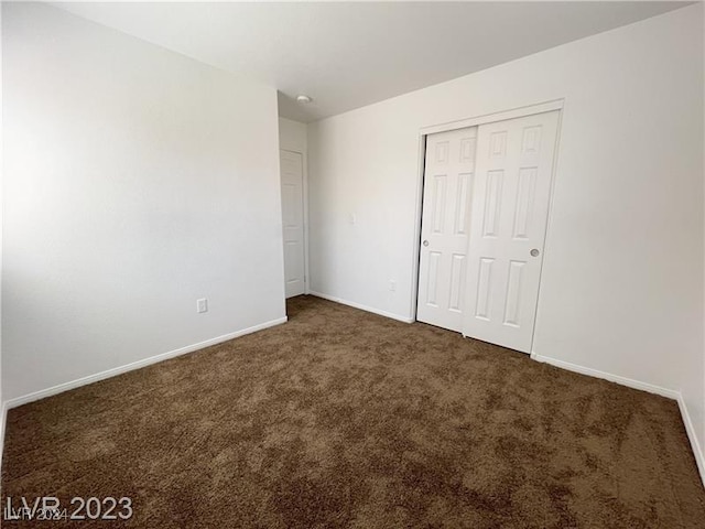 unfurnished bedroom featuring dark carpet and a closet