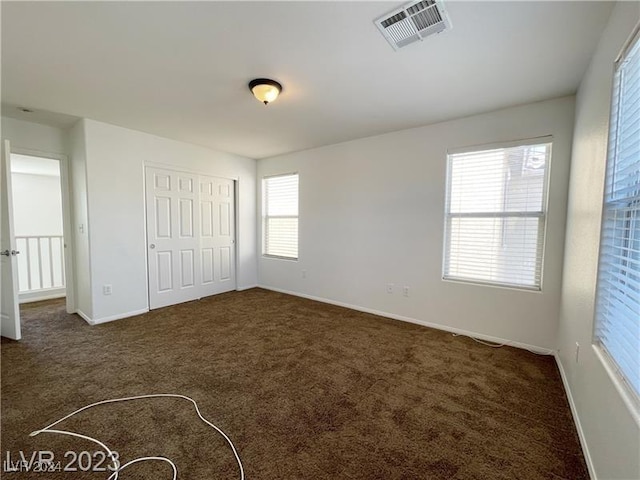 unfurnished bedroom with dark colored carpet and a closet