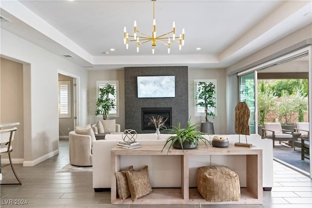 living room with a large fireplace, light hardwood / wood-style floors, a wealth of natural light, and a tray ceiling