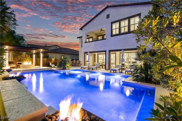 pool at dusk featuring a patio, a hot tub, and a fire pit