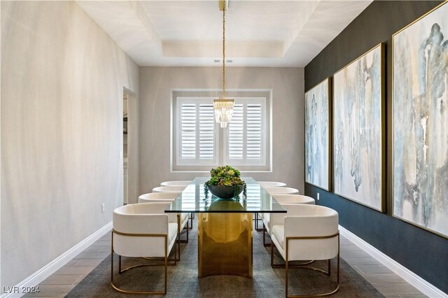 dining space with a chandelier, dark hardwood / wood-style floors, and a raised ceiling