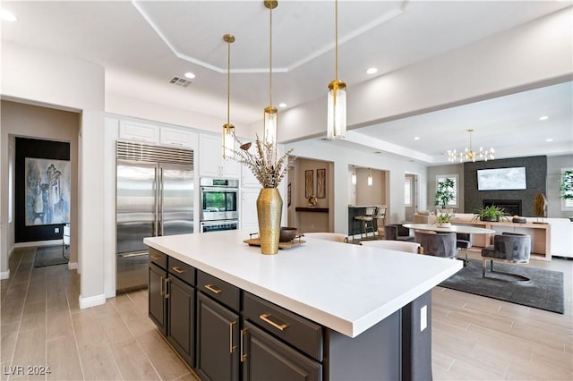 kitchen with white cabinetry, a center island, stainless steel appliances, light hardwood / wood-style flooring, and decorative light fixtures