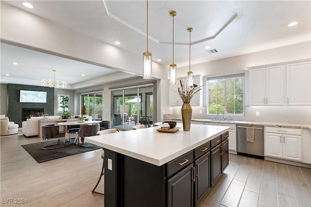 kitchen featuring dishwasher, a large fireplace, light hardwood / wood-style flooring, and white cabinetry