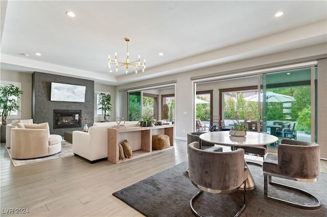 dining area with a fireplace, light hardwood / wood-style floors, and an inviting chandelier