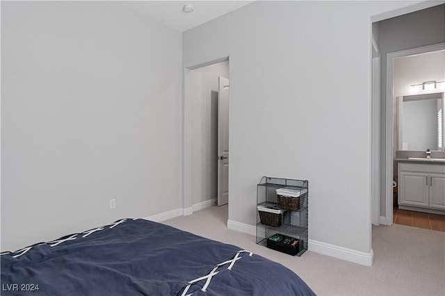 carpeted bedroom with ensuite bathroom and sink