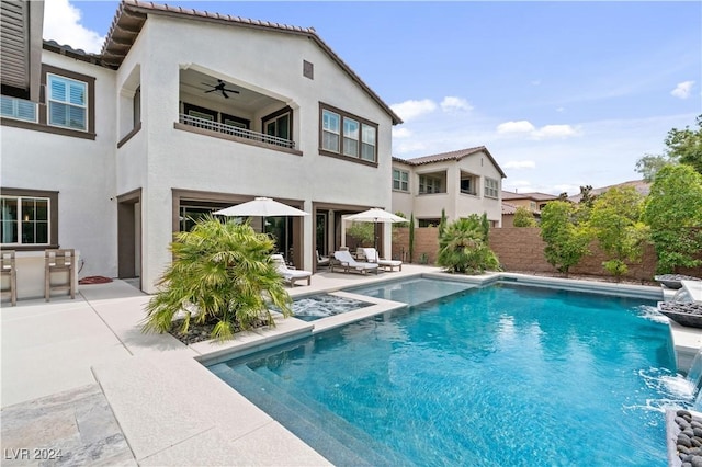 rear view of house featuring a fenced in pool, pool water feature, ceiling fan, a balcony, and a patio area