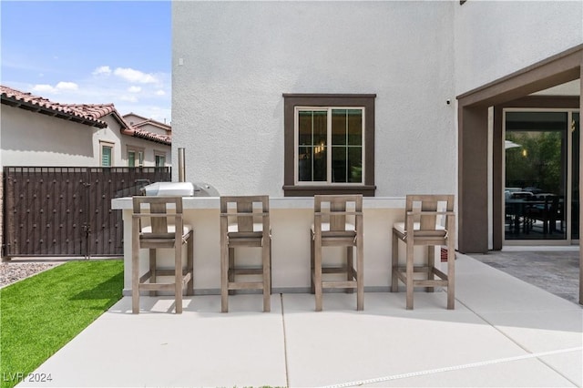 view of patio with area for grilling and a bar