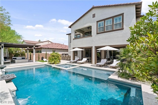 rear view of house featuring a swimming pool with hot tub, a balcony, ceiling fan, and a patio area