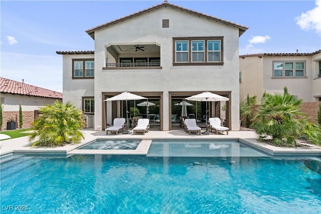 back of house with ceiling fan, a swimming pool with hot tub, a balcony, and a patio