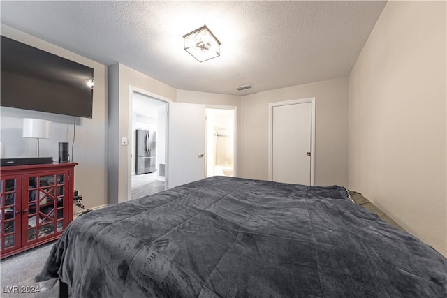 carpeted bedroom with stainless steel fridge and a textured ceiling