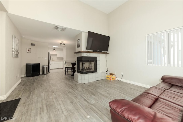 living room with a tiled fireplace and light hardwood / wood-style flooring