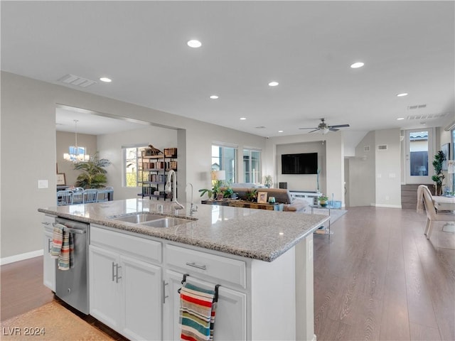 kitchen with light wood-type flooring, stainless steel dishwasher, a kitchen island with sink, sink, and white cabinets