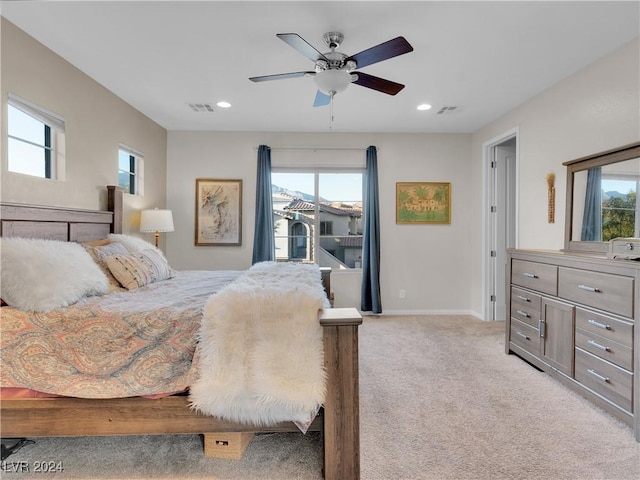 bedroom with light carpet, multiple windows, and ceiling fan