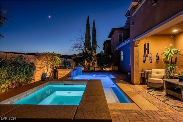 pool at dusk featuring an in ground hot tub