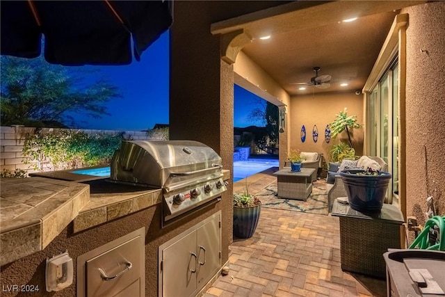 patio at night featuring ceiling fan, area for grilling, and an outdoor living space