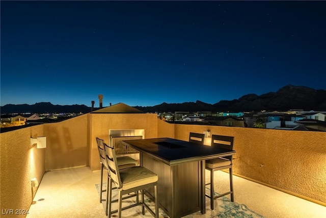 patio at twilight with a mountain view and a balcony